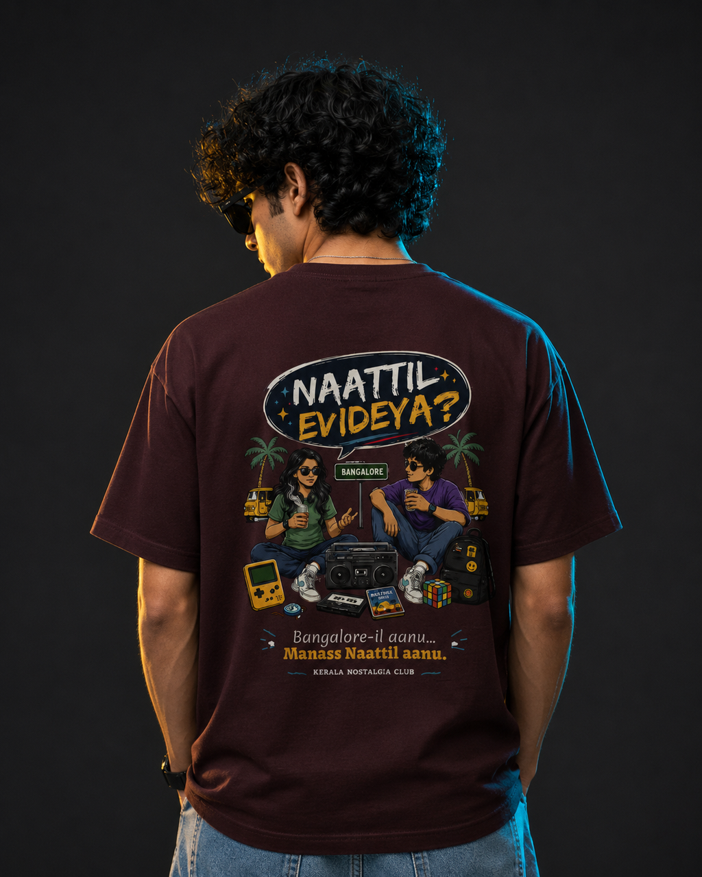 Person wearing a dark brown t-shirt with a graphic design and text on the back against a black background
