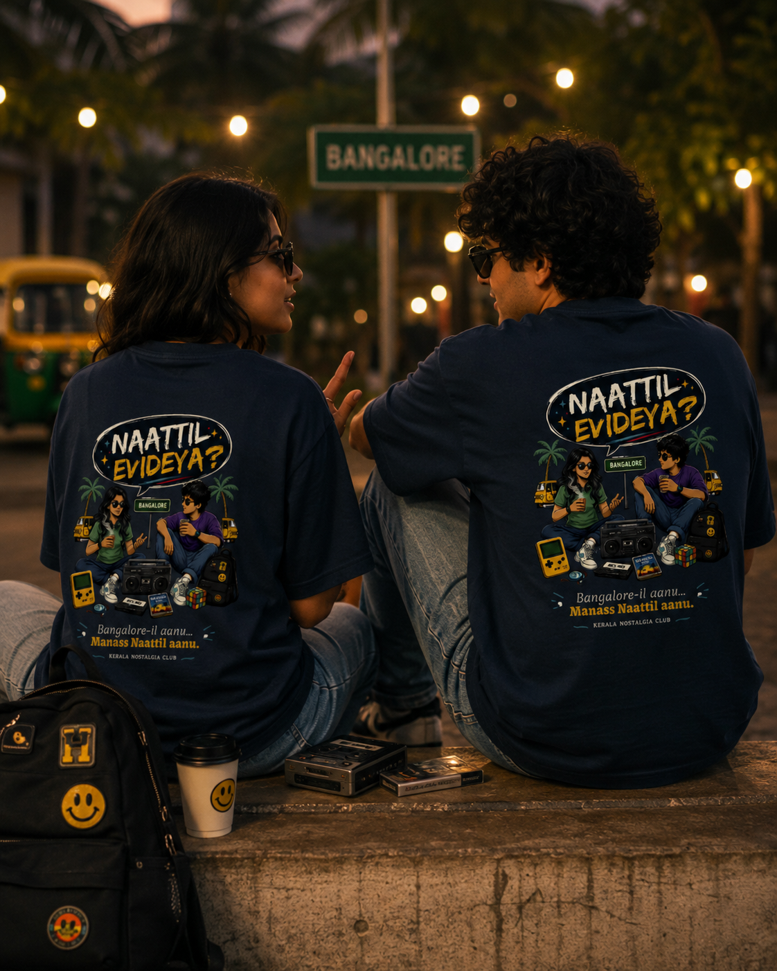 Two people sitting on a street at night wearing matching t-shirts with text and graphics.