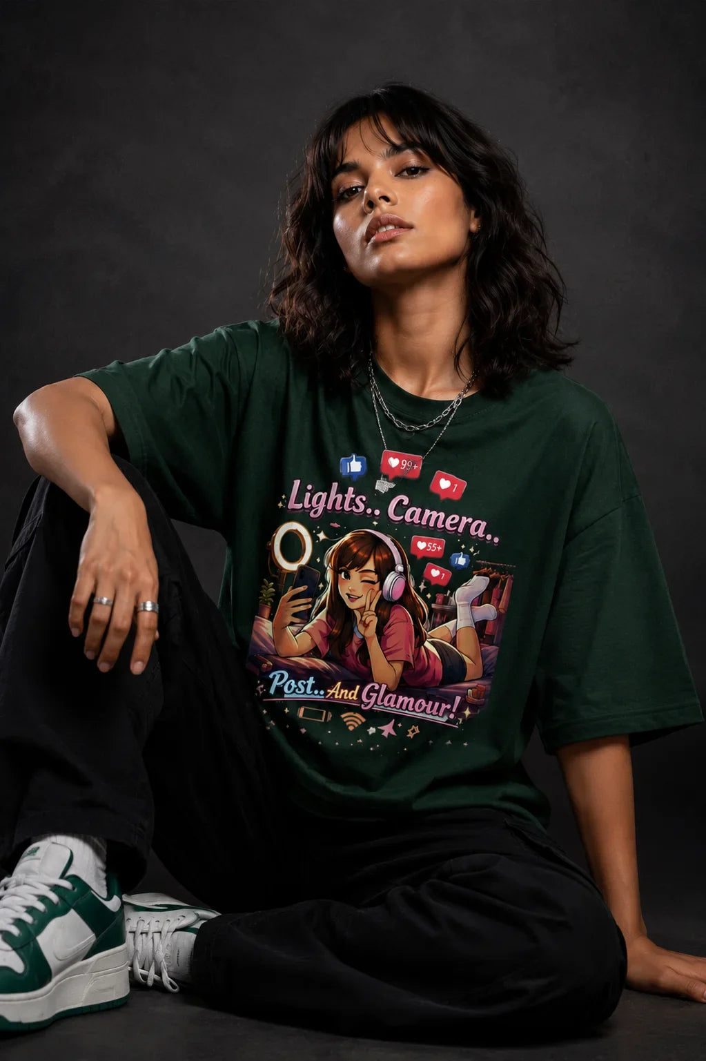 Person wearing a green t-shirt with graphic design and text, sitting against a dark background
