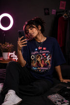 Person wearing a graphic t-shirt sitting in a room with a ring light and laptop.