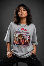 Person wearing a gray t-shirt with a graphic design on a dark background