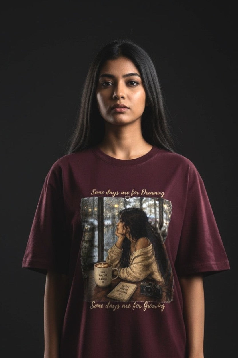 Person wearing a maroon t-shirt with a graphic design on a black background