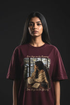 Person wearing a maroon t-shirt with a graphic design on a black background