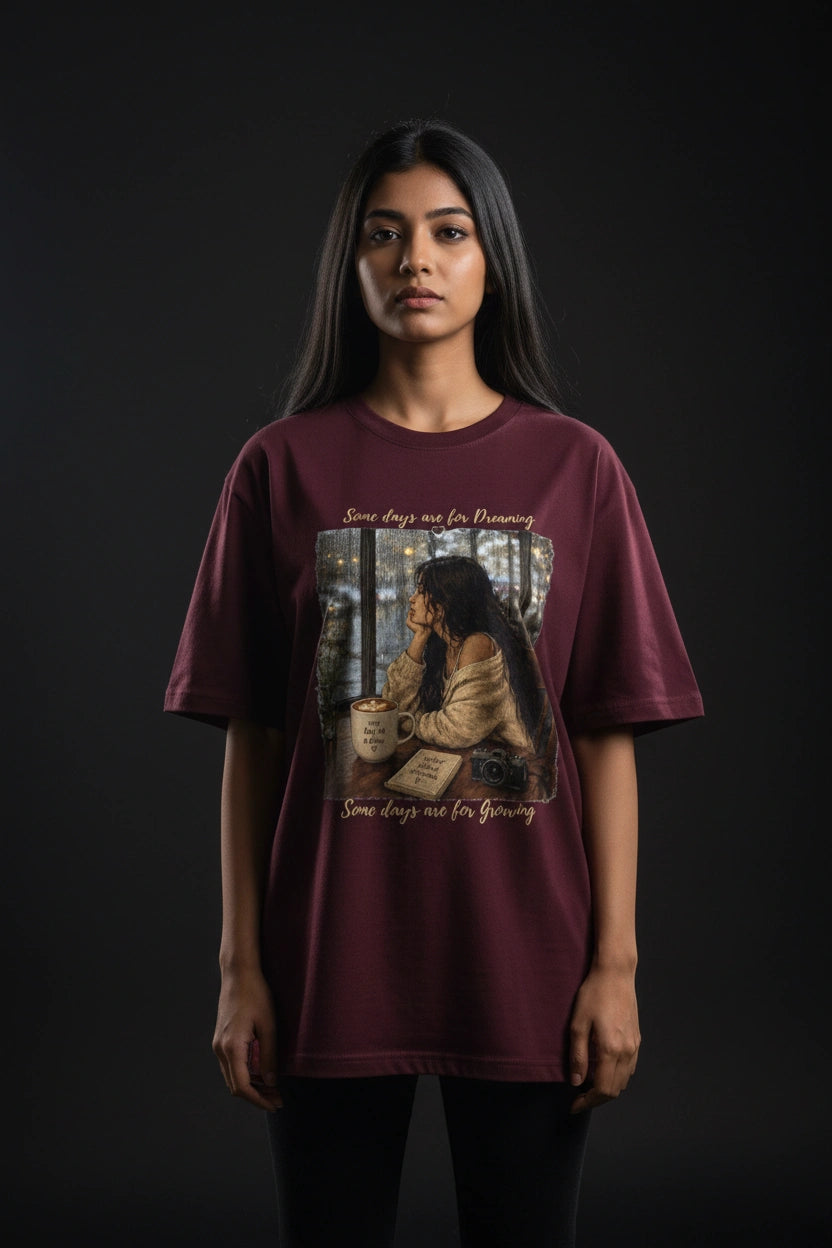 Person wearing a maroon t-shirt with a graphic design on a black background