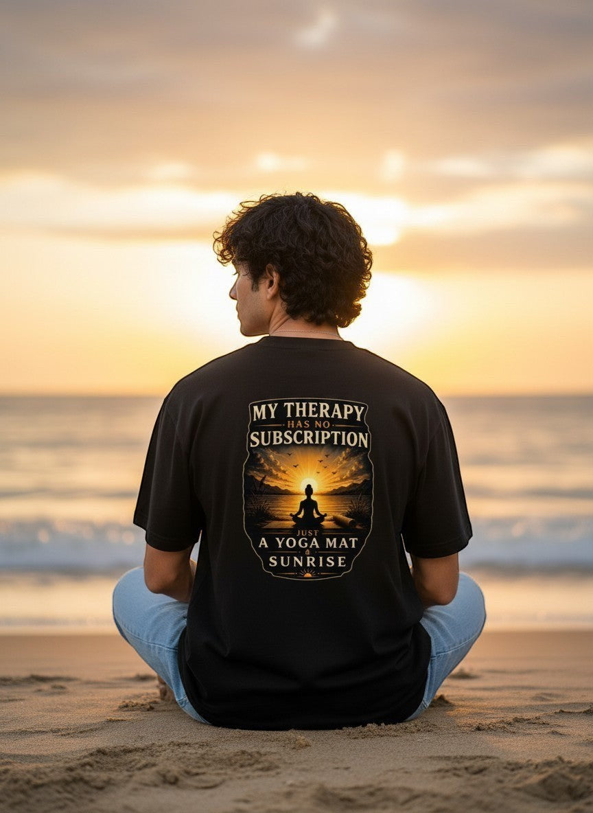 Black t-shirt with graphic: "My Therapy Has No Subscription Just A Yoga Mat & Sunrise". Features a meditating silhouette against a sunrise over the ocean.